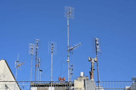 Various antennas on the roof of a residential apartment building, installation for communication and media such as tv, internet, smartphone and radio, blue sky, copy space, selected focusの写真素材