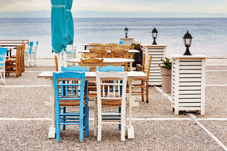 Wooden chairs and tables in blue and white in a taverna on the terrace next to the sea, tourist destination in Halkidiki, Greece, selected focusの写真素材