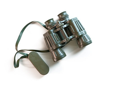 Used binoculars or field glasses with green rubber coating for adventure, discovery and observation in nature on a white background, copy space, top view from aboveの写真素材
