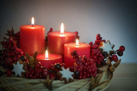 Advent wreath from willow wicker with four lighted red candles, cinnamon star cookies and berries, holiday decoration for Christmas time, copy space, selected focus, narrow depth of fieldの写真素材