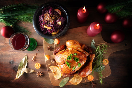 Roast chicken with red cabbage and wine on dark rustic wood with candles and Christmas decoration, festive poultry dinner for holidays, top view from above, copy space, selected focusの写真素材