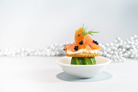 Party snack or appetizer from smoked salmon, carved cucumber, cracker and caviar with dill garnish,...