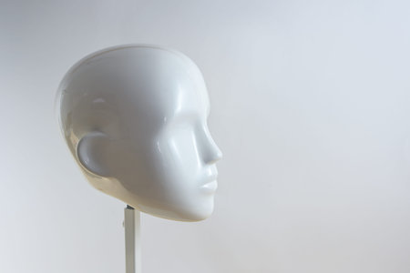 White neutral head of a mannequin figure in minimalist style on a metal stand against a light beige gray background, copy space, selected focusの写真素材