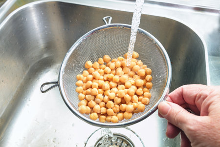 Pre-cooked canned chickpeas are rinsed with water in a sieve over the sink before being used in various dishes, healthy legumes are rich in protein, fiber and minerals, copy space, selected focusの写真素材