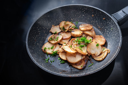 Roasted Jerusalem artichoke or topinambur (Helianthus tuberosus) with onions and parsley in a frying pan, root vegetable with healthy inulin for slimming and diabetes diet, copy space, selected focusの写真素材