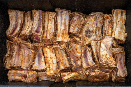 Seasoned and marinated beef short ribs are placed in a large black metal bowl, preparation for a barbecue party with many guests, top view from above, selected focusの写真素材
