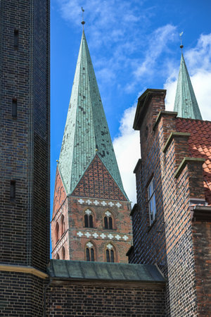 Tower of the Saint Mary church (Marienkirche) in Lubeck behind the town hall facade, historic buildings in brick architecture, typical for Northern Germanyの写真素材