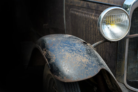 Headlight and mudguard from a rusty black vintage car, concept for a garage with repair and painting service, dark background, copy space, selected focus, narrow depth of fieldの写真素材