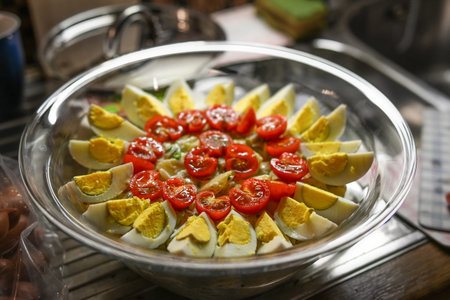 Potato salad with garnish of quartered eggs and cocktail tomatoes in a glass bowl in the kitchen,...