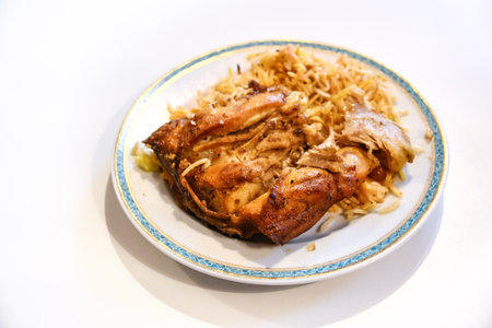 Chicken with biryani, the traditional Asian dish of fried spicy rice, portion on a plate and on a light table, copy space, selected focus, narrow depth of fieldの写真素材