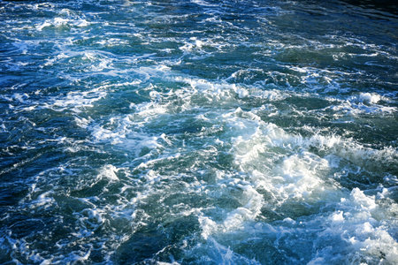 Churned up sea water with white foam behind a ship at full speed, ocean background texture, travel...