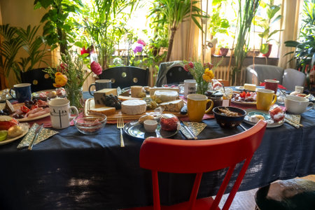Large dining table, fully set with cheese, sausage and more delicacies for a meal with family or friends in a living room, selected focus, narrow depth of fieldの写真素材