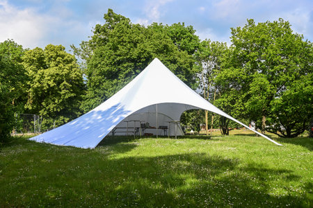 Large party tent made of white canvas with variable openings on a meadow in the park for a summer festival, copy space, selected focusの写真素材