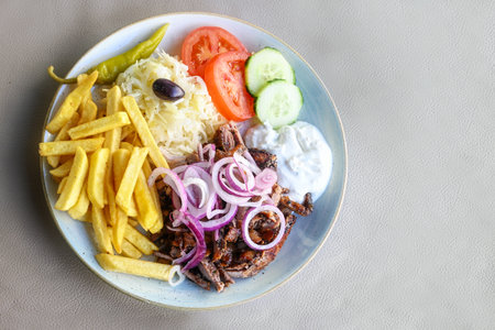 Gyros with a lot of onions, French fries, coleslaw, salad and tzatziki on a plate in a restaurant, Greek meat dish, copy space, high angle view from above, selected focusの写真素材
