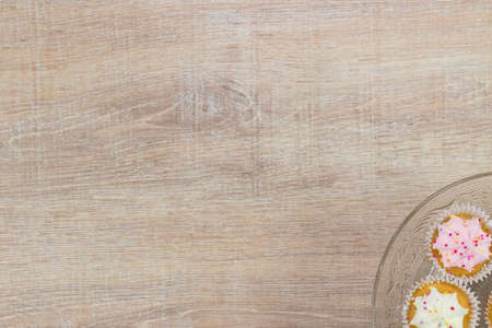 Colorful cupcakes on a wooden table background. Top view with space for your text.の写真素材