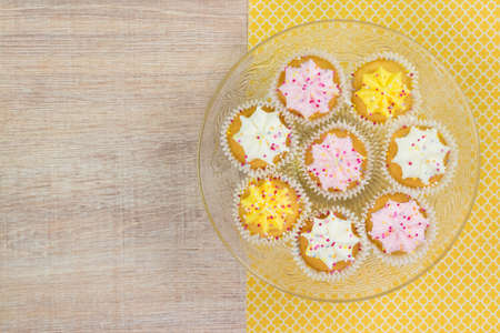 Colorful cupcakes on a wooden table background. Top view with space for your text.の写真素材