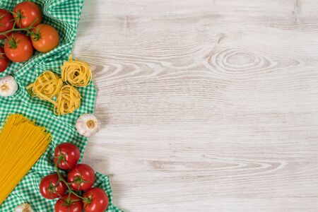 Italian food ingredients and checkered napkin on wooden table. Top view with space for your text.の写真素材