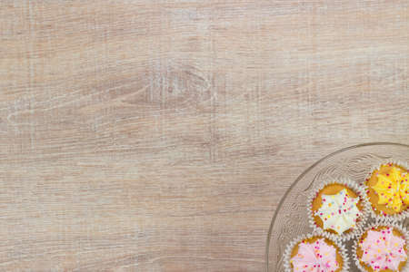 Colorful cupcakes on a wooden table background. Top view with space for your text.の写真素材