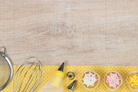 Colorful cupcakes and baking tools on a wooden table background. Top view with space for your text.の写真素材