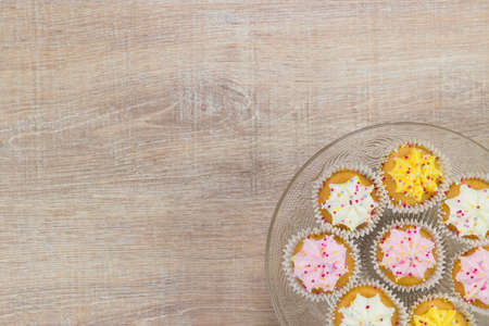 Colorful cupcakes on a wooden table background. Top view with space for your text.の写真素材