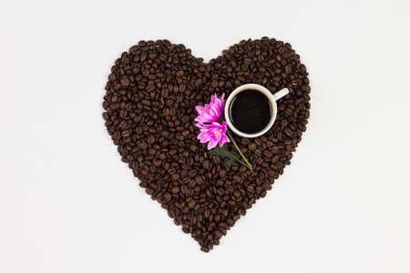 Coffee cup, flowers and coffee beans in a form of a heart isolated on white background.の写真素材