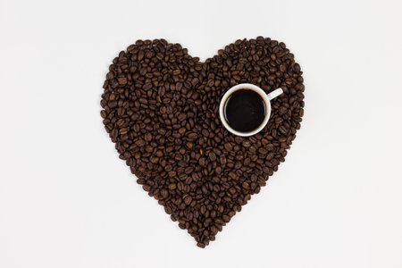Coffee cup and coffee beans in a form of a heart isolated on white background.の写真素材