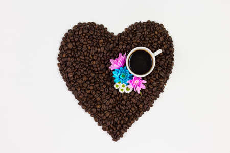 Coffee cup, flowers and coffee beans in a form of a heart isolated on white background.の写真素材