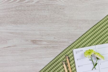Flat lay home office desk. Female workspace with flower, accessories, pen, pencil and diary on white wooden background. Top view feminine background.の写真素材