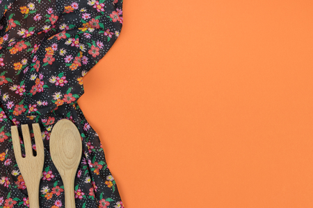 Set of wooden kitchen utensils. Floral pattern cloth napkin on empty orange background. Top view with space for your text.の写真素材