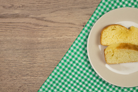 Freshly baked homemade cake slices and green checkered tablecloth on wooden table. Top view with copy space.の写真素材