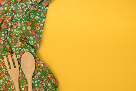 Set of wooden kitchen utensils. Floral pattern cloth napkin on empty yellow background. Top view with space for your text.の写真素材