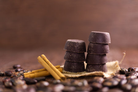 Handmade chocolate surrounded by cocoa beans on wood