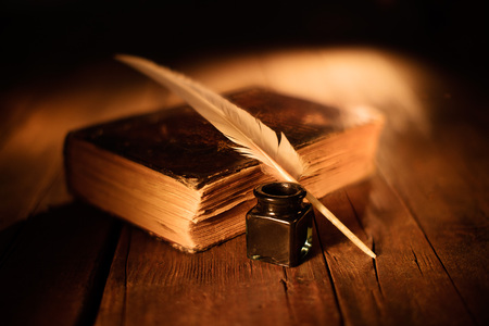 old book with quill pen and inkwell on wooden tableの写真素材