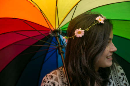 Girl playing with a rainbow umbrella in the garden.の写真素材