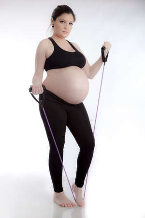 Pregnant woman doing gymnastic exercises on white backgroundの写真素材