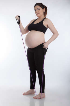 Pregnant woman doing gymnastic exercises on white backgroundの写真素材