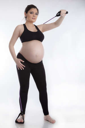 Pregnant woman doing gymnastic exercises on white backgroundの写真素材