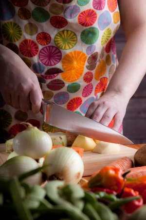 Woman prepare healthy vegetarian food with potatoes, carrots, onions, peppers, beans, chives and zucchiniの写真素材