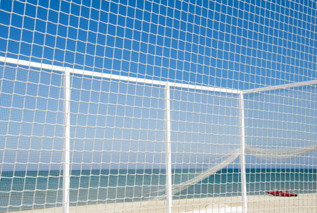 Volleyball net with red boat on the beach.の写真素材
