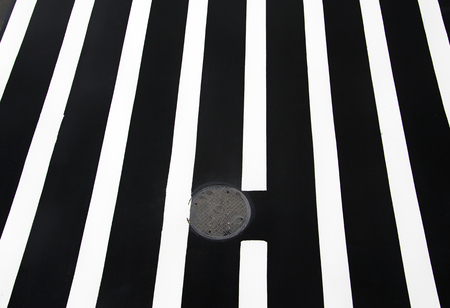Pedestrian crossing road marking, white lines over black asphalt pavement with almonds.の写真素材