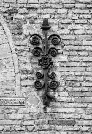 Ancient decorative wrought iron on brick wall (black and white)の写真素材