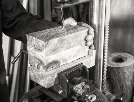 Carpenter workplace- Man using a drill press on wood (antique effect, sepia).の写真素材