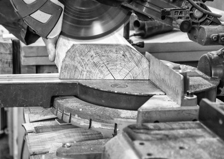 Carpenter workplace- Man using circular saw to cut wood. (Black and white).