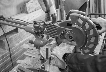 Carpenter workplace- Man using circular saw to cut wood. (Black and white).の写真素材