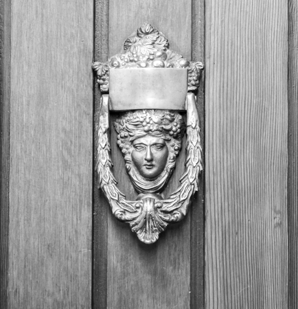 Ancient door knoker on an wodden door (black and white).の写真素材