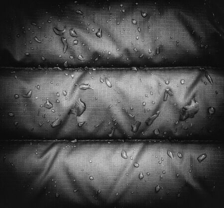 A close up of blue rain jacket waterproof fabric with water droplets, vignetting effect, black and white.の写真素材
