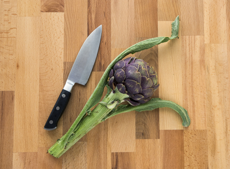 Fresh globe artich is on wood background with knife.の写真素材