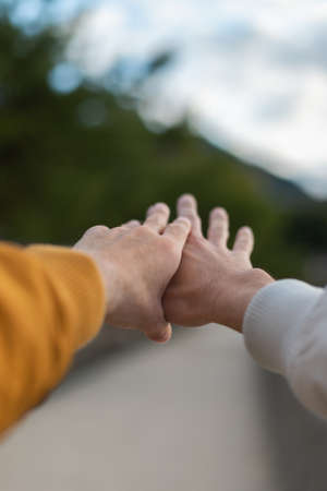 Gay couple extending their hands forward -  homosexuality, same-sex marriage, gay and love concept - first person view - two male hands holding each other.の写真素材
