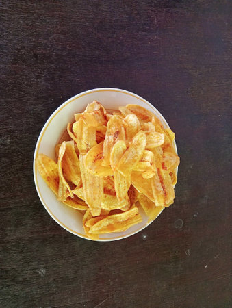 Crispy banana chips in bowl on black background, top viewの写真素材