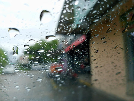 Rain drops on the windshield of a car with a blurred background.の写真素材